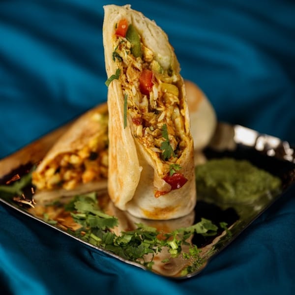 Two Chaska Indian Restaurant wraps filled with chicken, vegetables, and rice, garnished with cilantro.