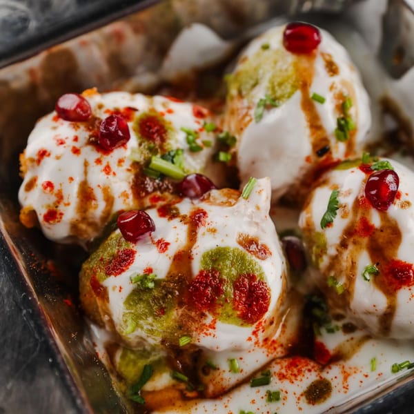 Close-up of Chaska Indian Restaurant's Dahi Bhalla, topped with yogurt, chutneys, spices, and pomegranate seeds.